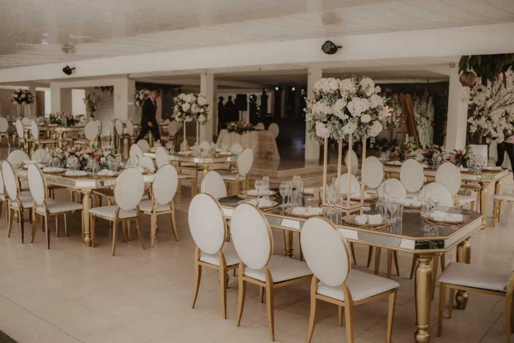Salón blanco con mesas y sillas doradas
